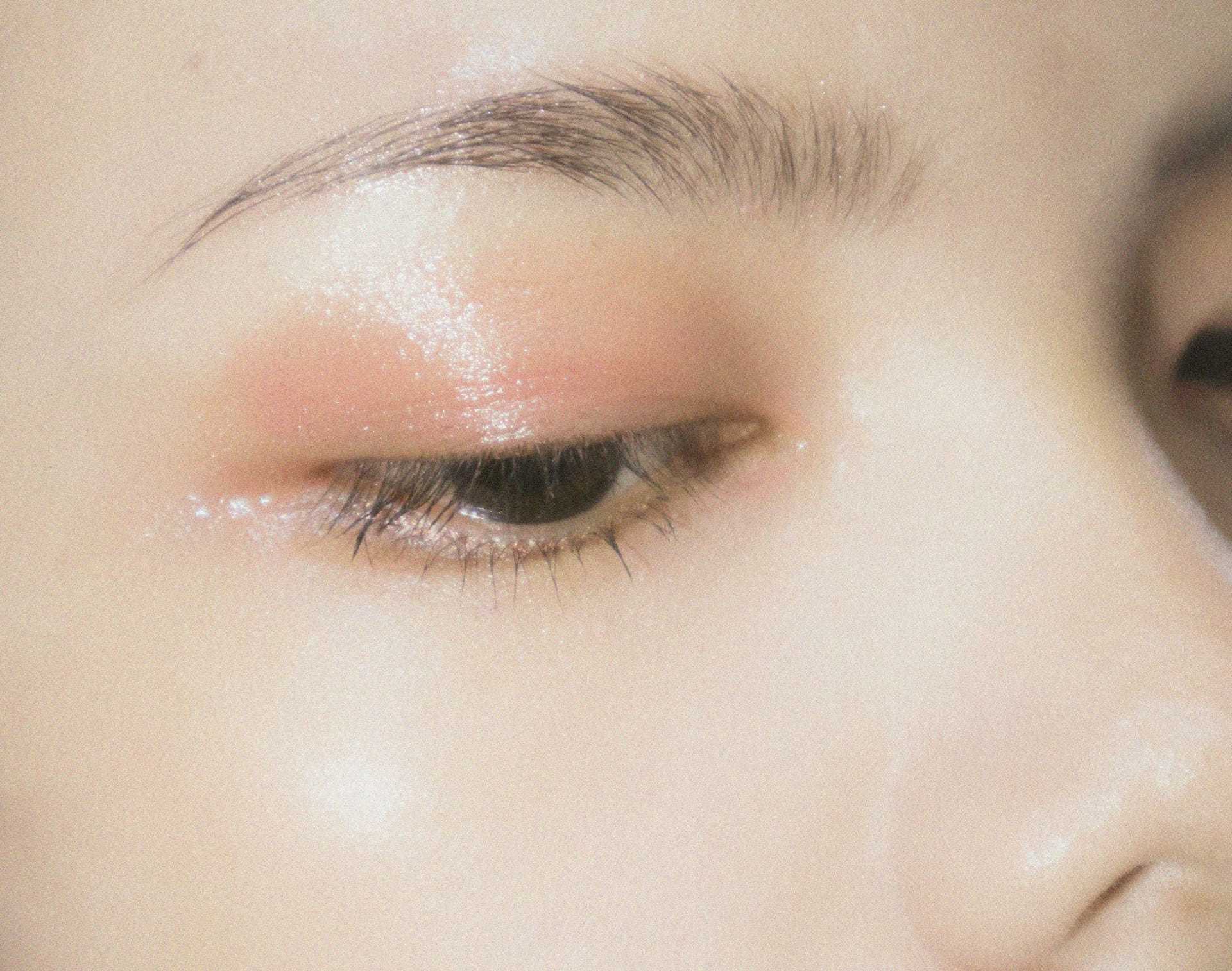Close-up of a person's eye with natural makeup and glossy eyelid.