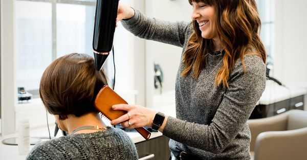 Hair stylist drying client's hair in a salon.